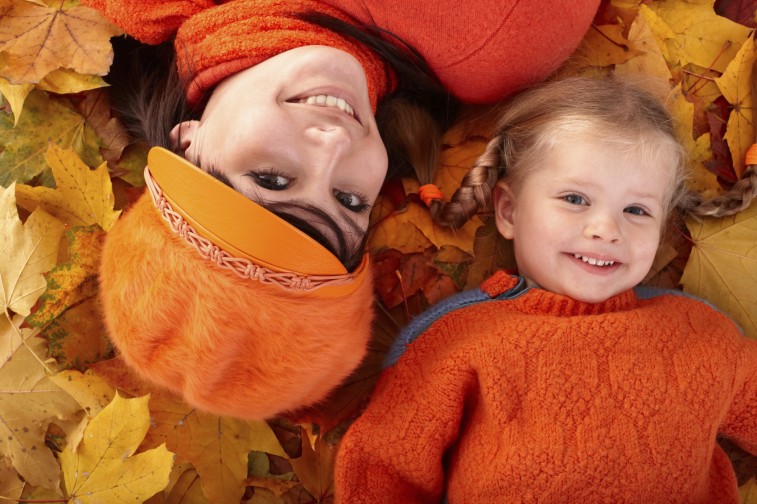 Happy family with child on autumn orange leaf.