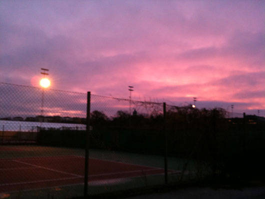 Utomhus-tennisbana i morgonsken.