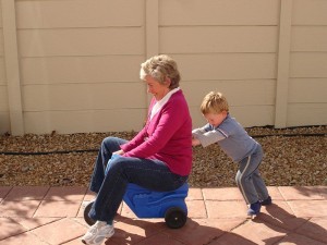 800px-Child_pushing_grandmother_on_plastic_tricycle